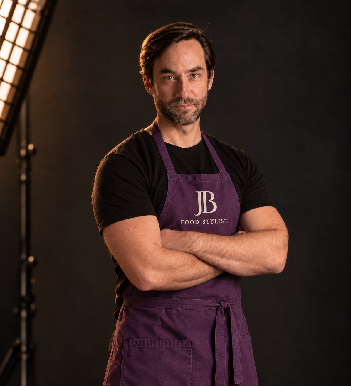 José Bernardo Ferber de braços cruzados no estúdio, avental roxo bordado com o logo JB Food Stylist